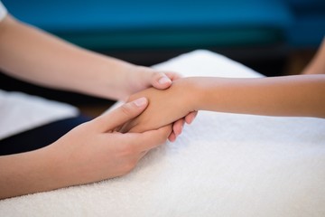 Fototapeta na wymiar Close-up of female therapist holding hands while examining on