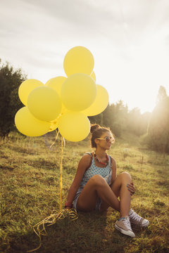 Girl Sitting on The Grass and Holding Balloons