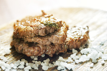 beef steak with herbs and salt on cutting board in sunlight 