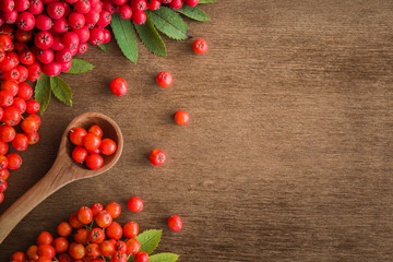 Rowan berries on the brown wooden table. Recipe background. Autumn concept. Empty place for a text or object. Top view.