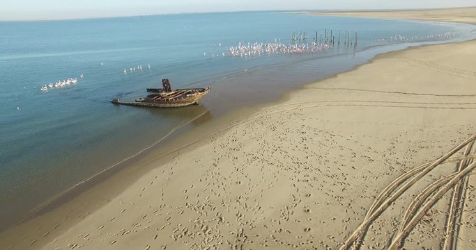 Aerial view drone video of Pelican Point Lodge and Paratus lighthouse on sand beach peninsula, shipwreck and lagoon with ocean background with ships at Namibia's Atlantic west coast