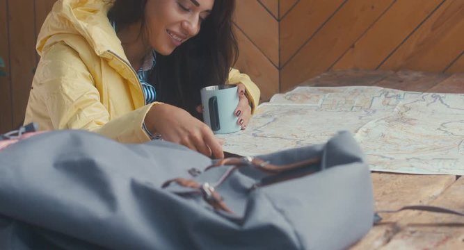 Attractive female hiker millennial planning a trip, looking at the paper map and drinking tea. 4K UHD 60 FPS