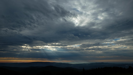 Fototapeta na wymiar Cloudy sky with sun rays during sunrise in Romania