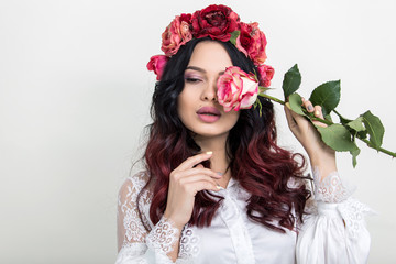 Beauty Fashion Model Woman face. Portrait with Red Rose flower. Red Lips and Nails. Beautiful Brunette Woman with Luxury Makeup and Manicure.