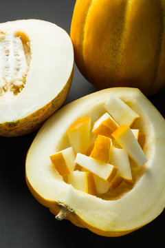 Whole and half of a yellow melon isolated on a black background.