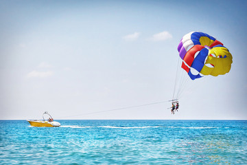 Parachuting in Turkey. Parasailing with boat over sea in Alanya in beautiful summer day. Tropical beach vacation. - Powered by Adobe