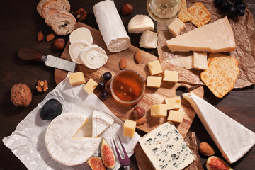 Variety of different cheese with wine, fruits and nuts. Camembert, goat cheese, roquefort, gorgonzolla, gauda, parmesan, emmental