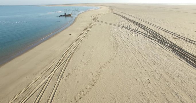 Aerial view drone video of Pelican Point Lodge and Paratus lighthouse on sand beach peninsula, Walvis Bay harbour and lagoon with ocean background with ships at Namibia's Atlantic west coast