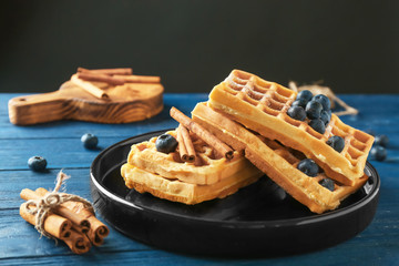 Tasty homemade waffles with cinnamon sticks and blueberries on plate