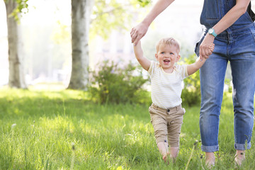 Fototapeta premium Mother and cute baby boy walking on green grass in park