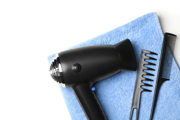 Hair dryer, combs and towel on white background