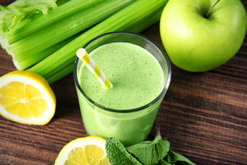 Glass of green healthy juice with ingredients on wooden table