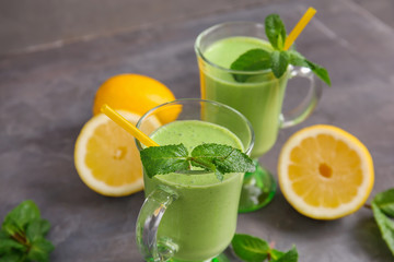 Glasses of green healthy juice with fruit and mint on table