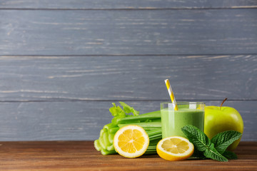 Glass of green healthy juice with ingredients on wooden table