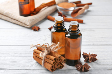 Beautiful composition with essential cinnamon oil in glass bottles on wooden table