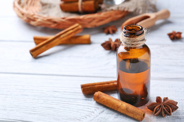 Beautiful composition with essential cinnamon oil in glass bottle on wooden table