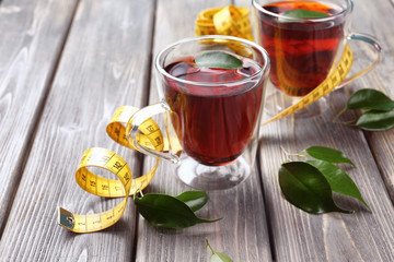 Cups of tea and measuring tape on wooden table. Weight loss concept