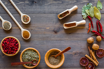 Variety of spices and dry herbs in bowls on wooden kitchen table background top view
