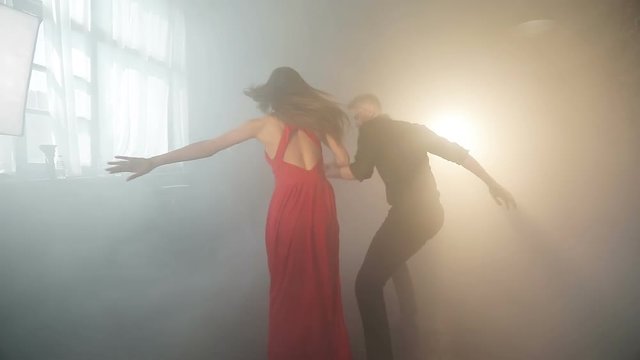 A bright couple performs a beautiful tango in the smoke.