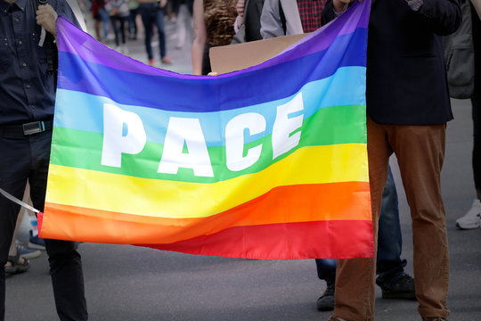 Concept of sexual minority. People holding rainbow flag of peace movement during gay parade outdoors