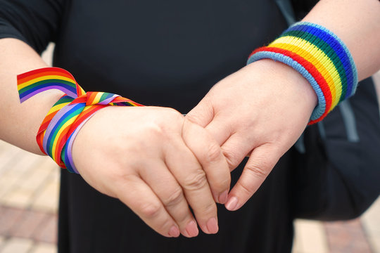 Concept of sexual minority. Female hands with rainbow wristbands  outdoors