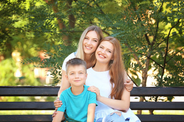 Lesbian couple with foster son in park. Adoption concept