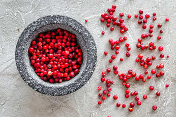 mortar with berries, herbs and spices ingredients on stone background top view