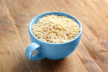 Cup of long grain brown rice on table