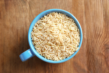 Cup of long grain brown rice on table