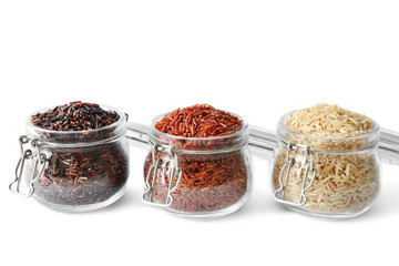 Different types of rice in glass jars on white background