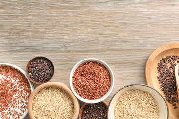 Different types of rice in bowls and plate on wooden table