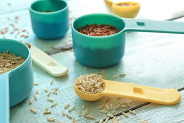Different types of rice in  measuring scoops on wooden table