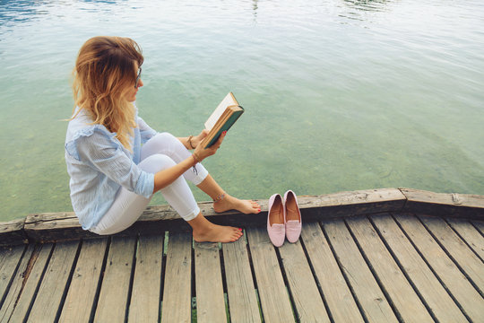 Pretty woman enjoying on the lake and reading a book.