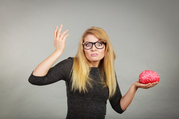 Woman in eyeglasses being confused holding brain