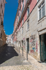 Fototapeta na wymiar Lisbon in Portugal, typical street, sloping alley with colored houses and typical pavement 
