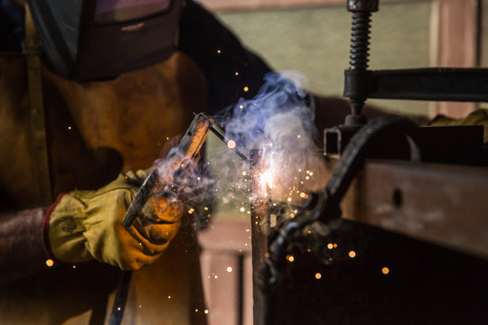 A man in a workshop using an industrial metal grinder to grind down stainless steel