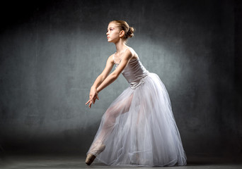 Fototapeta na wymiar Ballerina. Cute little girl posing and dancing in studio. The girl is studying ballet. Dark background.