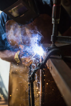 A man in a workshop using an industrial metal grinder to grind down stainless steel