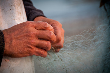 Fisherman repairs his net at the Adriatic Sea. Fano Italy