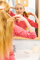 Woman combing her long hair in bathroom