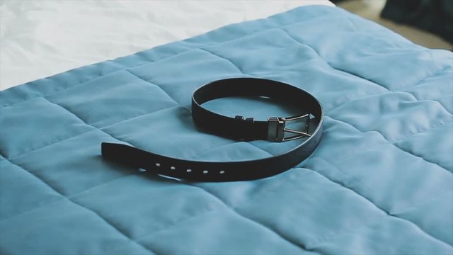 businessman puts on a belt that lies on the bed