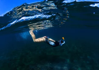 Foto auf Acrylglas Snorkeling woman dives to sea bottom. Snorkeling girl in full-face snorkeling mask. © Elya.Q