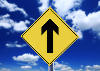 Yellow road sign with cloudscape with arrow symbol