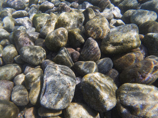 Fototapeta na wymiar Seashore pebbles underwater photo texture. Seaside beach with big stones.