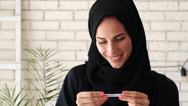 Picture of happy young arabic woman holding positive pregnancy test. 