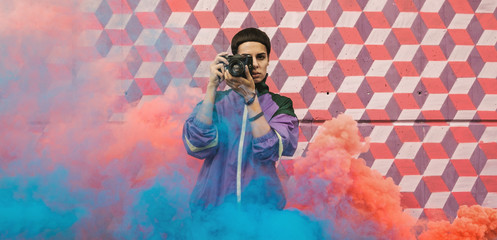Hip young girl with old analog camera surrounded with smoke.