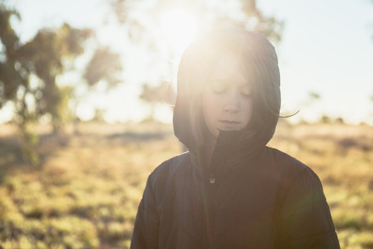 girl in winter parka in the country, with sun flare
