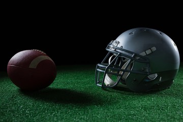 American football head gear and football on artificial turf
