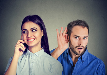 A cheating girlfriend. Curious man secretly listening to a happy woman talking on mobile phone with her lover