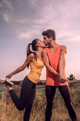 two young people, man woman, kissing couple, stretching legs arms, fitness, outdoors, nature, sky, sunny day, clouds
